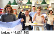 Happy sports supporters with flag of Argentina, rejoicing winning game with beer and snacks in pub. Стоковое видео, видеограф Яков Филимонов / Фотобанк Лори