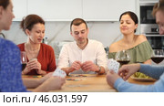 Young man deeply engrossed in friendly poker game with group of friends of different nationalities in relaxed home atmosphere around kitchen table. Стоковое видео, видеограф Яков Филимонов / Фотобанк Лори