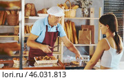 Mature salesman putting and weighing small pastry and give to girl buyer in bakery shop. Стоковое видео, видеограф Яков Филимонов / Фотобанк Лори