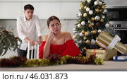 Upset young couple arguing among themselves before X-mas Eve near Christmas tree in kitchen at home. Стоковое видео, видеограф Яков Филимонов / Фотобанк Лори