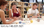 Pottery workers paint ceramic plates together at a table. Стоковое видео, видеограф Яков Филимонов / Фотобанк Лори