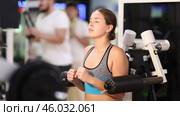 Girl in gym performs exercises for arm muscles using simulators and fitness center equipment. Стоковое видео, видеограф Яков Филимонов / Фотобанк Лори