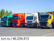Multicolored trucks stand in a row in a parking lot, long distance cargo transportation (2020 год). Редакционное фото, фотограф Коханова Наталья / Фотобанк Лори