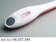 Modern basal body thermometer showing temperature on grey background. Стоковое AI-изображение, AI-художник Иван Рябоконь / Фотобанк Лори