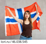 Sad young woman holding flag of Norway against unicoloured background. Стоковое фото, фотограф Яков Филимонов / Фотобанк Лори