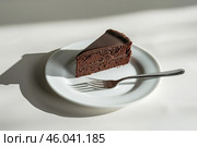 Piece of Sacher torte on white Plate. Brown portion slice of famous Sachertorte chocolate cake with apricot jam against white background. Typical Austrian original chocolate sponge cake dessert. Стоковое AI-изображение, AI-художник Марина Демидюк / Фотобанк Лори