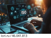 Человек работает за ноутбуком с голографическим экраном, на котором среди многочисленных значков ярко светятся буквы ISO. Стоковое AI-изображение, AI-художник Ярославский Максим / Фотобанк Лори