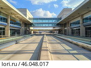 Empty airport road leading to skybridge connecting terminals on sunny day. Стоковое AI-изображение, AI-художник Иван Рябоконь / Фотобанк Лори