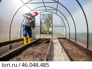 A male farmer pours new soil, soil for a new greenhouse. The concept of spring vegetable planting, greenhouse installation and farming. Стоковое фото, фотограф Photojuli / Фотобанк Лори
