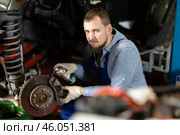 Mechanic applying anti-rust liquid to bolts on car wheel hub. Стоковое фото, фотограф Яков Филимонов / Фотобанк Лори