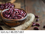 Wooden bowl overflowing with kidney beans on rustic table. Стоковое AI-изображение, AI-художник Иван Рябоконь / Фотобанк Лори