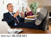 Adult employee playing games on smartphone at workplace in office. Стоковое фото, фотограф Яков Филимонов / Фотобанк Лори