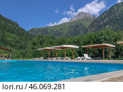 Бассейн для отдыха и купания высоко в горах. Отдых у воды на свежем воздухе. Шезлонги для отдыха и принятия солнечных ванн возле бассейна с голубой водой. Летний отдых в горах. Стоковое фото, фотограф Эдуард Белкин / Фотобанк Лори