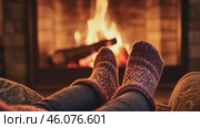 Cozy, warm feet in knitted gray socks by the glowing fireplace. Point of view. Charming winter ambiance. Closeup of legs in knit socks near fire stove in the wooden cabin, in rustic room or farmhouse. Стоковое AI-видео, аниматор Марина Демидюк / Фотобанк Лори
