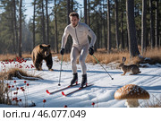 Яркий лыжник на зимних лыжах среди леса с дикими животными и растительностью в теплую погоду. Медведь, заяц, ягоды, грибы. Стоковое AI-изображение, AI-художник Сергей Никифоров-Гордеев / Фотобанк Лори