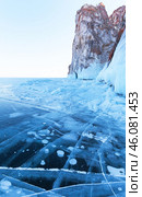 Beautiful winter landscape of frozen Baikal Lake. View of famous cape Sagan-Khushun called Three Brothers and blue ice with cracks, bubbles and ice hummocks near Olkhon Island. Winter travels and outdoors. Стоковое фото, фотограф Виктория Катьянова / Фотобанк Лори