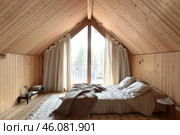Cozy attic bedroom with wooden walls and ceiling inviting relaxation. Стоковое AI-изображение, AI-художник Иван Рябоконь / Фотобанк Лори