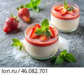 Two elegant servings of strawberry panna cotta sit on a rustic stone tabletop, garnished with fresh mint leaves and ripe strawberries, evoking a sense of indulgence and freshness. Стоковое AI-изображение, AI-художник Ольга Игнашина / Фотобанк Лори
