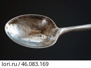 Tarnished silver spoon showing signs of age and wear on dark background. Стоковое AI-изображение, AI-художник Иван Рябоконь / Фотобанк Лори