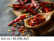 Wooden spoon showing dried chili flakes and powder with whole chilis in background. Стоковое AI-изображение, AI-художник Иван Рябоконь / Фотобанк Лори
