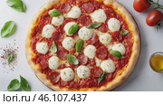 Top view footage of italian pizza with tomato sauce, dry and spicy salsiccia, mozzarella, basil leaves, olive oil, appetizing. Italian cuisine and gastronomic tour concept. Culinary video blog. Стоковое AI-видео, аниматор Ирина Михайличенко / Фотобанк Лори