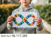 A colorful sign of the endless rainbow of autism in the hands of a boy. World Autism Awareness Day, the Autistic rights movement. Society's acceptance of autism. Стоковое AI-изображение, AI-художник Photojuli / Фотобанк Лори