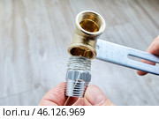 Plumbing flax is wrapped around stainless steel threaded reducer nipple, preparing it for installation into brass pipe fitting. Стоковое фото, фотограф Владимир Григорьев / Фотобанк Лори