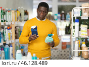 Before buying in household shop, African male customer choose glass cleaner spray. Стоковое фото, фотограф Яков Филимонов / Фотобанк Лори
