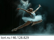 Dancer leaping gracefully in a white tutu on stage with dramatic lighting and dust in the air during a performance at night. Стоковое AI-изображение, AI-художник Sergey Grishin / Фотобанк Лори