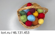 Time-lapse video of colorful balls of wool yarn for knitting and crochet in placed by female hand in wicker basket on light table. Wooden hooks and knitting needles nearby. Flat lay, close-up. Стоковое видео, видеограф Виктория Катьянова / Фотобанк Лори