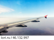 View of airplane wing against clear blue sky during daytime flight over tranquil landscape. Стоковое фото, фотограф Сергей Толмачёв / Фотобанк Лори