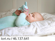 Cute Newborn Baby Lying on the Back and Plays with Colorful Toys. Little Three Month Child Takes a Toy. Portrait of Playful Neonate Toddler. Concept of Childhood, New Life, Baby Care. Top View. Стоковое фото, фотограф Марина Демидюк / Фотобанк Лори