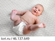 Cute Newborn Baby Lying on the Back in a Child Crib on White. Top View of Little Energetic Child. Playful Neonate Toddler Looks Around and Waving Hands. Concept of Childhood, New Life, Baby Care. Стоковое фото, фотограф Марина Демидюк / Фотобанк Лори