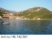 Canj, Montenegro 07.20.2024 Boats and a shore with vacationers, sunbathers and swimmers. Hotels, sun umbrellas, Adriatic waves, buoys. Beach tourism. Vacation travel. Summer day. Pebble rock beach. Редакционное фото, фотограф Юлия Петровская / Фотобанк Лори