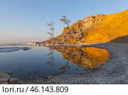 Baikal Lake in May. Bright spring landscape with melting ice on rocky beach near Khuzhir of Olkhon Island at sunset. Cape Burkhan is reflected in calm blue water, white ice floes float in Small Sea. Стоковое фото, фотограф Виктория Катьянова / Фотобанк Лори