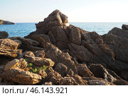 Waves gently crash against the rugged rocks while the sun sets over the horizon. Experience the serene beauty of this coastal location filled with natural wonders. Canj, Montenegro, Adriatic sea (2024 год). Стоковое фото, фотограф Юлия Петровская / Фотобанк Лори