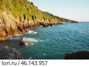 Waves gently crash against the rugged rocks while the sun sets over the horizon. Experience the serene beauty of this coastal location filled with natural wonders. Canj, Montenegro, Adriatic sea (2024 год). Стоковое фото, фотограф Юлия Петровская / Фотобанк Лори
