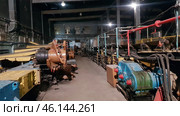 An industrial workshop, probably a repair shop or maintenance shop for mining equipment in Vorkuta. Inside the room are various machines, including conveyor belts, gearboxes, hydraulic devices and metal structures that are used in the coal industry. In the foreground is a blue gearbox with red plugs, and in the center is a massive, rusty-colored drilling or drive mechanism. Numerous cables and pipes run along the walls. The general condition of the room is worn out, with an abundance of dust, oil and dirt, which is typical for such industries.The photo well conveys the atmosphere of hard work of miners and the importance of equipment maintenance in the harsh conditions of Vorkuta. (2021 год). Редакционное фото, фотограф Анна Кривицкая / Фотобанк Лори