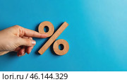 Wood percentage sign in a human hand. Blue studio background, copy space. Symbol percent. Seasonal sale, discount. Rate for finance, return. Investment ROI, credit, mortgage, tax, marketing, promotion. Стоковое AI-видео, аниматор Марина Демидюк / Фотобанк Лори