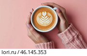 Coffee Cup. Female Hands in Wool Sweater Holding Cappuccino. Top view Woman with White Latte Mug. Close Up. Hygge Winter Mood. Cappuccino with Leaf Shape Art Milk Foam on Pale Pink Desk. Thick Froth. Стоковое AI-видео, аниматор Марина Демидюк / Фотобанк Лори