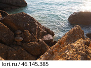 Waves gently crash against the rugged rocks while the sun sets over the horizon. Experience the serene beauty of this coastal location filled with natural wonders. Canj, Montenegro, Adriatic sea (2024 год). Стоковое фото, фотограф Юлия Петровская / Фотобанк Лори