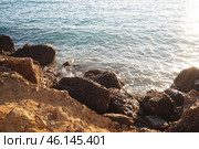 Waves gently crash against the rugged rocks while the sun sets over the horizon. Experience the serene beauty of this coastal location filled with natural wonders. Canj, Montenegro, Adriatic sea (2024 год). Стоковое фото, фотограф Юлия Петровская / Фотобанк Лори