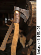 An old battle or utility axe driven into a wooden log. Its metal blade appears hardened and slightly worn, and the handle is made of roughly worked wood and is wrapped in leather straps for a better grip.The background is blurred, but you can see details of a rustic interior, perhaps a hunting lodge or a forge. An animal skull is visible, adding an air of antiquity and tradition to the scene. Such an axe could have been used as a tool for chopping wood or in combat, typical of Vikings, ancient Russian warriors, or medieval craftsmen. Стоковое фото, фотограф Анна Кривицкая / Фотобанк Лори