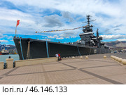 The cruiser "Mikhail Kutuzov", which is a museum ship in the city of Novorossiysk. This Project 68-bis warship was part of the USSR Navy for a long time, and then was turned into a museum, becoming one of the main attractions of the city.The side of the ship with the number "105", which indicates its affiliation with the Navy.You can see the flag garland - a ship decoration used during celebrations.Antennas and radar installations on the masts of the cruiser.A group of tourists on board, inspecting the ship.Mooring ropes secured to the pier.The protective paint of the hull is a characteristic dark gray color. (2023 год). Редакционное фото, фотограф Анна Кривицкая / Фотобанк Лори