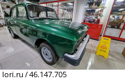 Retro car "AZLK Moskvich-2140", painted in a rich green color. This Soviet-made car was produced at the Moscow Automobile Plant (AZLK) in the 1970-1980s. The car is in the USSR Museum, surrounded by display cases with porcelain figurines, crystal and other items of Soviet life.Classic Soviet car with a characteristic design.Green body paint, shiny chrome bumper.The signature "AZLK" emblem and the "Moskvich-2140" model on the front.Museum setting, glass display cases with items from the Soviet era.Caution, wet floor! - warning sign on the floor.Retro-style museum interior with red design elements. (2023 год). Редакционное фото, фотограф Анна Кривицкая / Фотобанк Лори