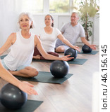 A group of elderly amateurs with a girl instructor perform Eka Pada Rajakapotasana with a soft ball. Стоковое фото, фотограф Яков Филимонов / Фотобанк Лори