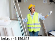Woman in hardhat and vest counting drywall sheets. Стоковое фото, фотограф Яков Филимонов / Фотобанк Лори