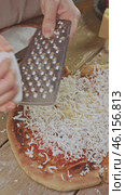 The chef expertly grates cheese on an almost finished pizza. Then the pizza is sent to the oven so that the cheese melts. Стоковое видео, видеограф Strunov David / Фотобанк Лори