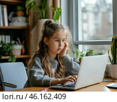 Девочка делает уроки онлайн, сидя за столом у окна. Стоковое AI-изображение, AI-художник Руслан Лесков / Фотобанк Лори