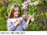 Close up little girl in a lilac dress touches the bloom lilac flowers while walking in park and smells the scent of spring flowers. Spring time and awakening. Children and nature. High quality photo. Стоковое фото, фотограф Ирина Михайличенко / Фотобанк Лори
